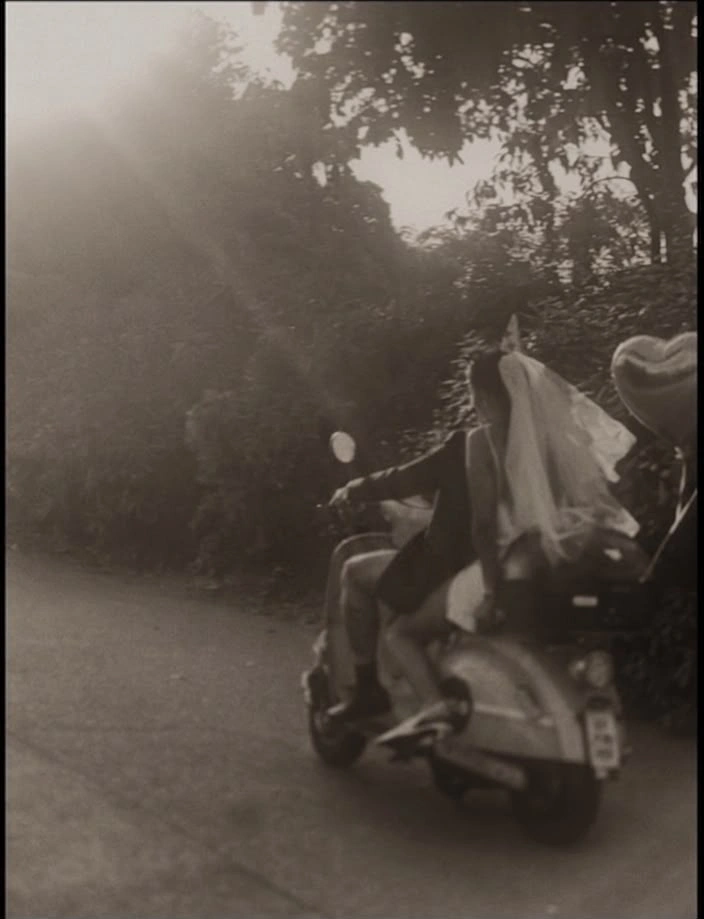 Joana and Cristian riding off on a scooter, her veil in the wind